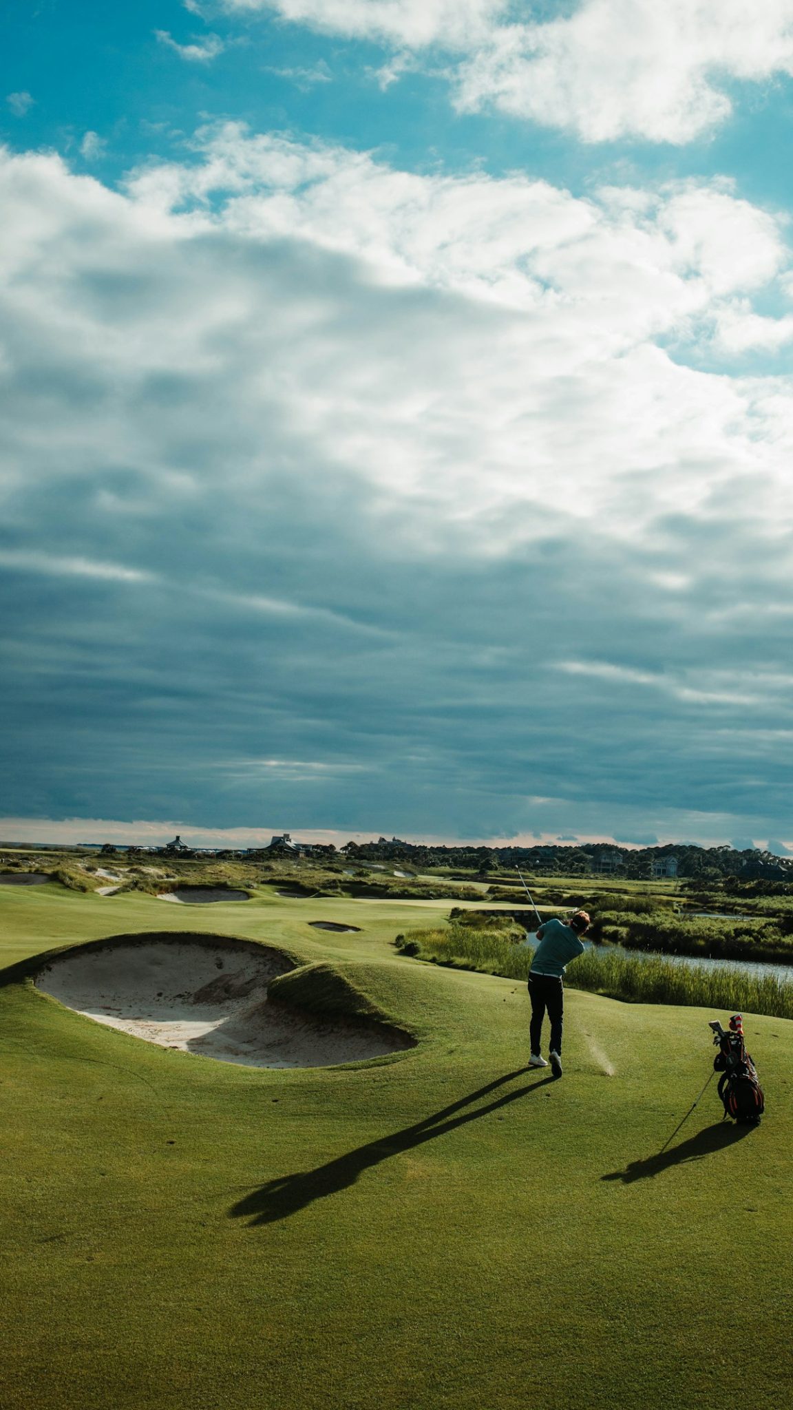 Golfer hitting approach shot on links course near bunker