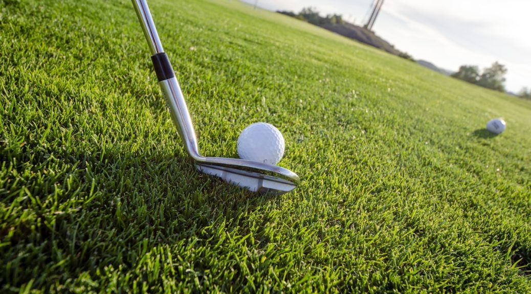 Golfer executing golf swing on course