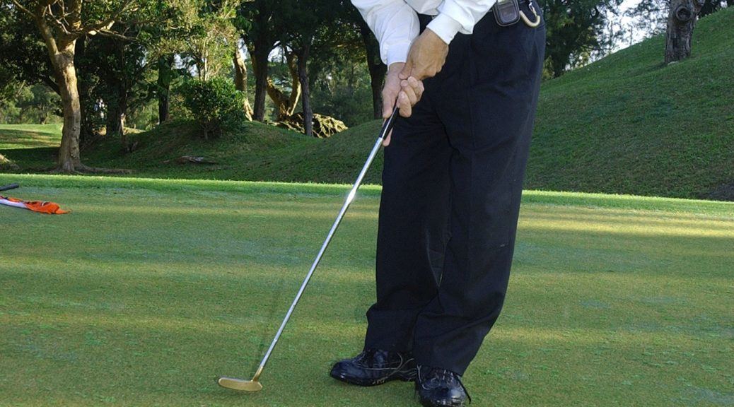 Golfer putting on the green to complete a hole
