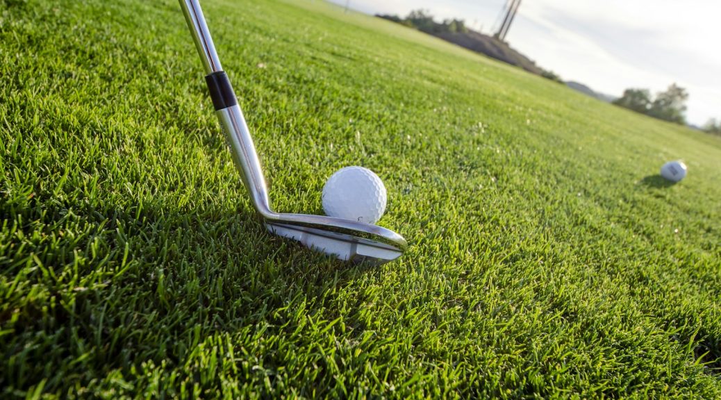 Wedge clubface behind a golf ball ready for a chip shot