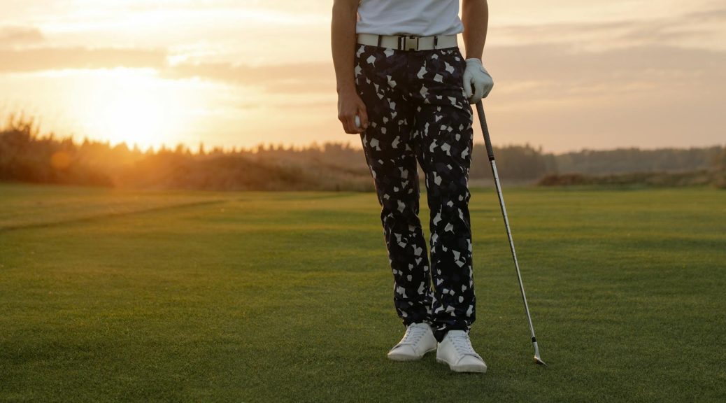 Golfer wearing patterned pants on a golf course at sunset - Best Golf Pants for Men 2026
